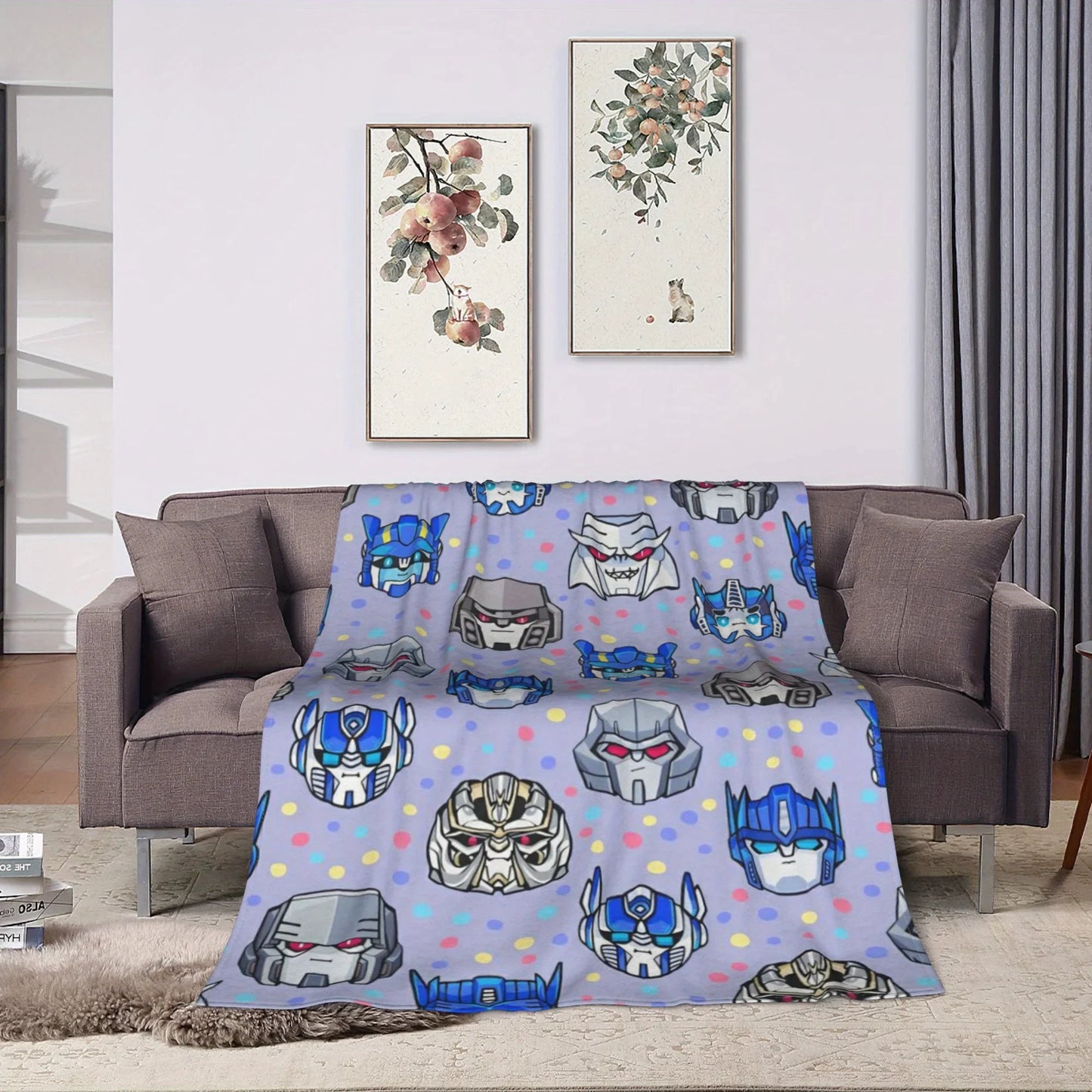 Plaid gris décoré de têtes de robots Transformers, posé sur un canapé moderne – Transformers.