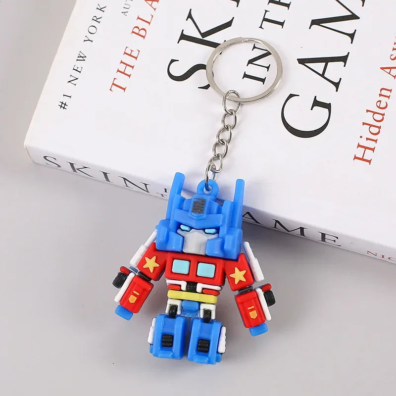 Porte-clés figurine robot coloré en plastique, posé sur un livre blanc – Transformers.