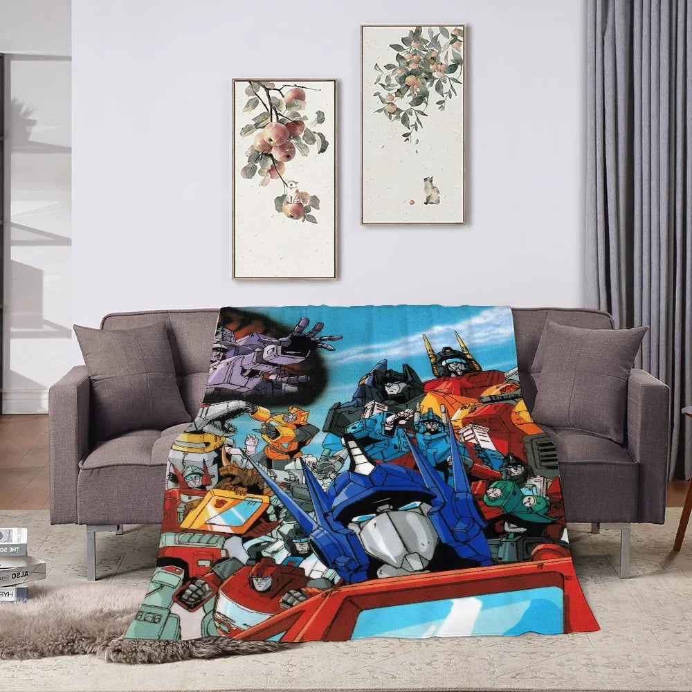 Plaid décoratif Transformers avec robots colorés et Optimus Prime sur canapé gris, salon moderne – Transformers.