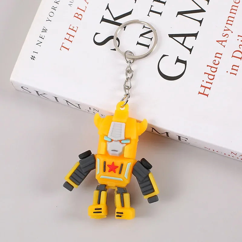 Porte-clés figurine robot jaune style dessin animé, sur fond de livre blanc – Transformers.