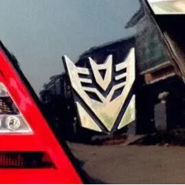 Autocollant logo Decepticon argenté sur vitre de voiture, reflet urbain en arrière-plan – Transformers.