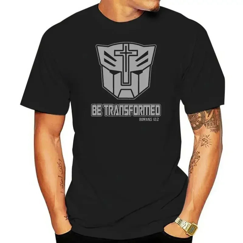 Homme portant un t-shirt noir avec logo Transformers, croix et texte Be Transformed – Transformers.