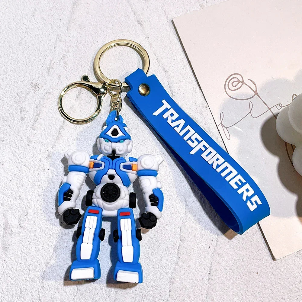 Porte-clés robot bleu et blanc en silicone, figurine debout, décor blanc, style cartoon – Transformers.