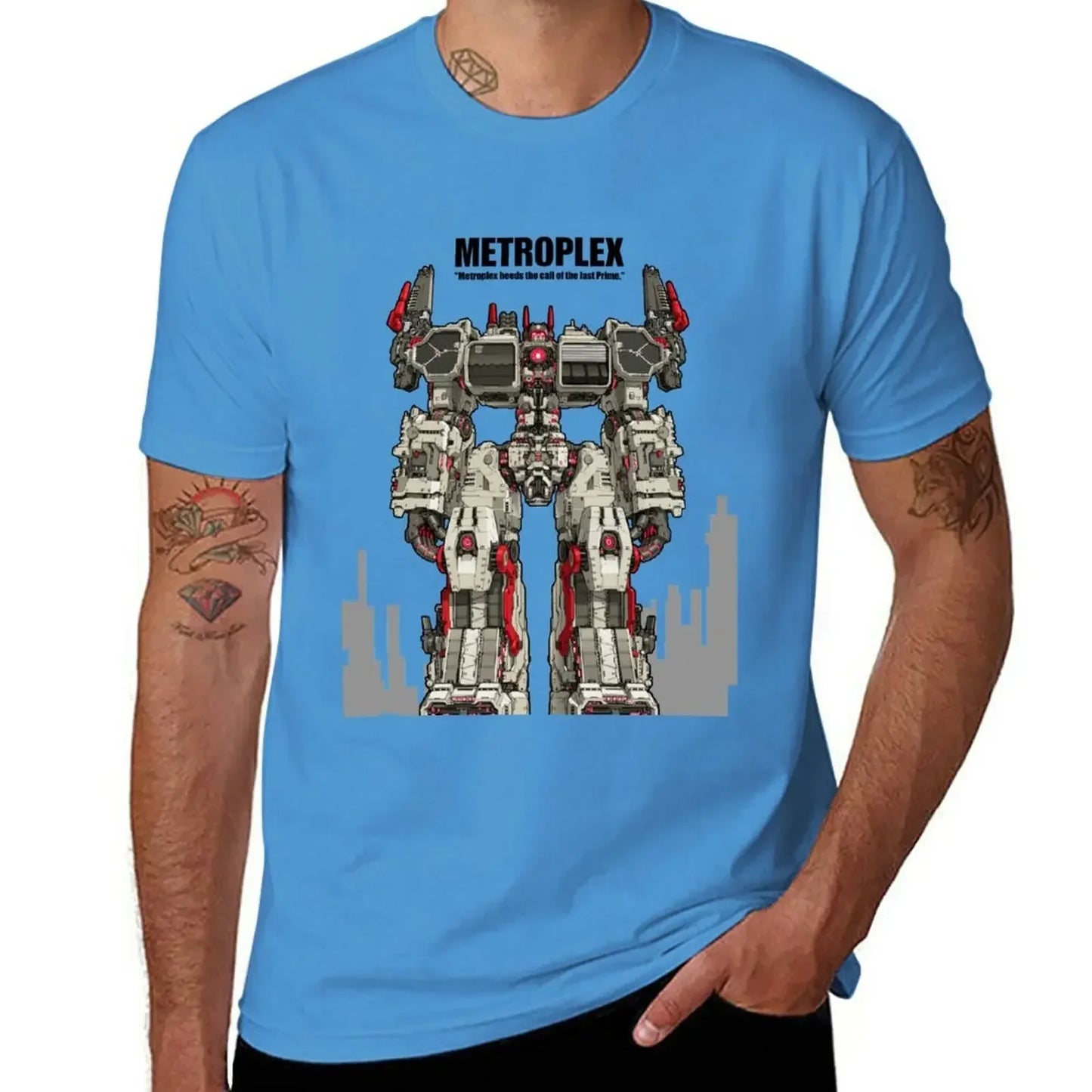 T-shirt bleu avec illustration du robot Metroplex debout, détails rouges et décors urbains – Transformers.