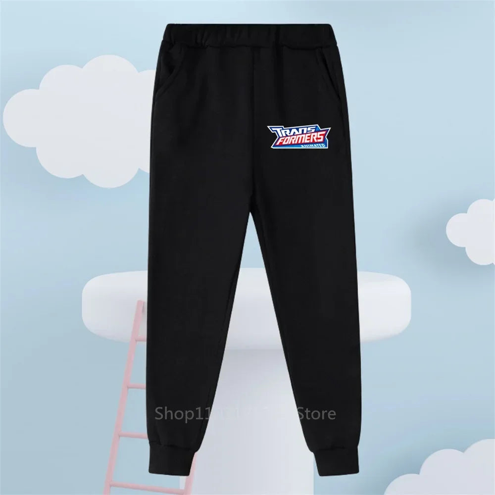 Pantalon noir avec logo coloré Transformers, fond bleu décoré de nuages et échelle – Transformers.