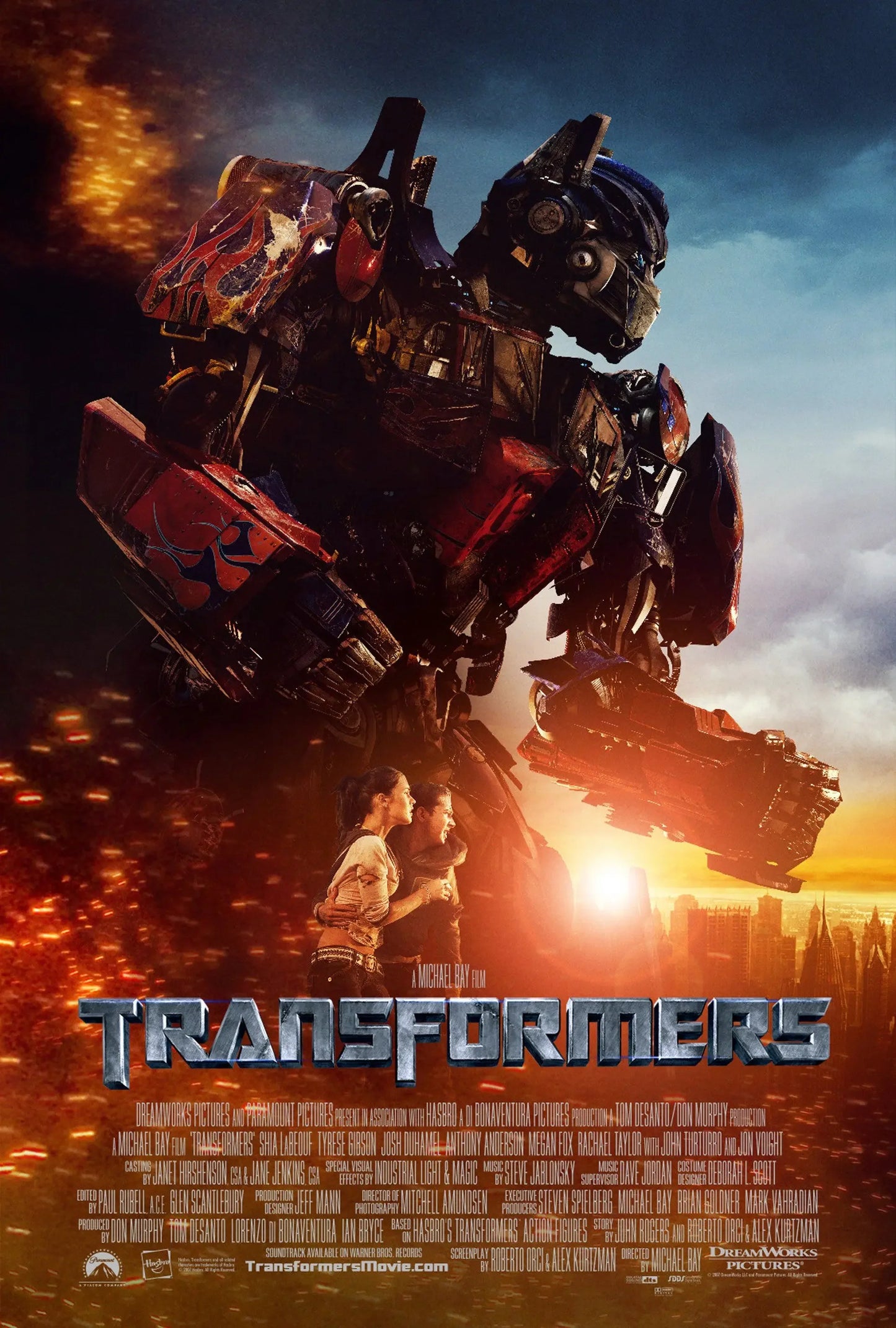 Affiche du film Transformers avec un robot géant, deux humains, décor urbain au coucher du soleil – Transformers.