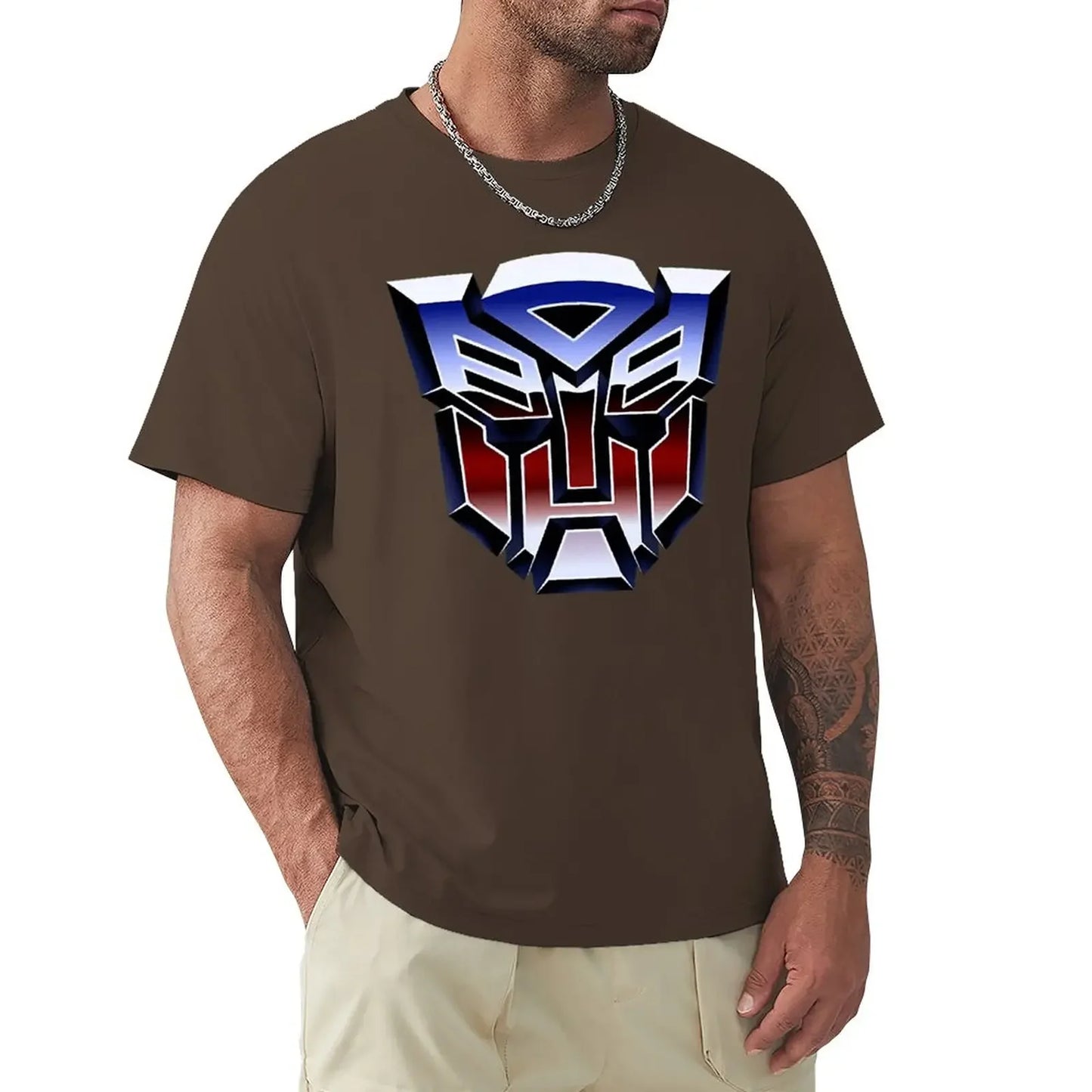 Homme portant un t-shirt marron avec grand logo Autobots métallisé bleu rouge, bras tatoué – Transformers.