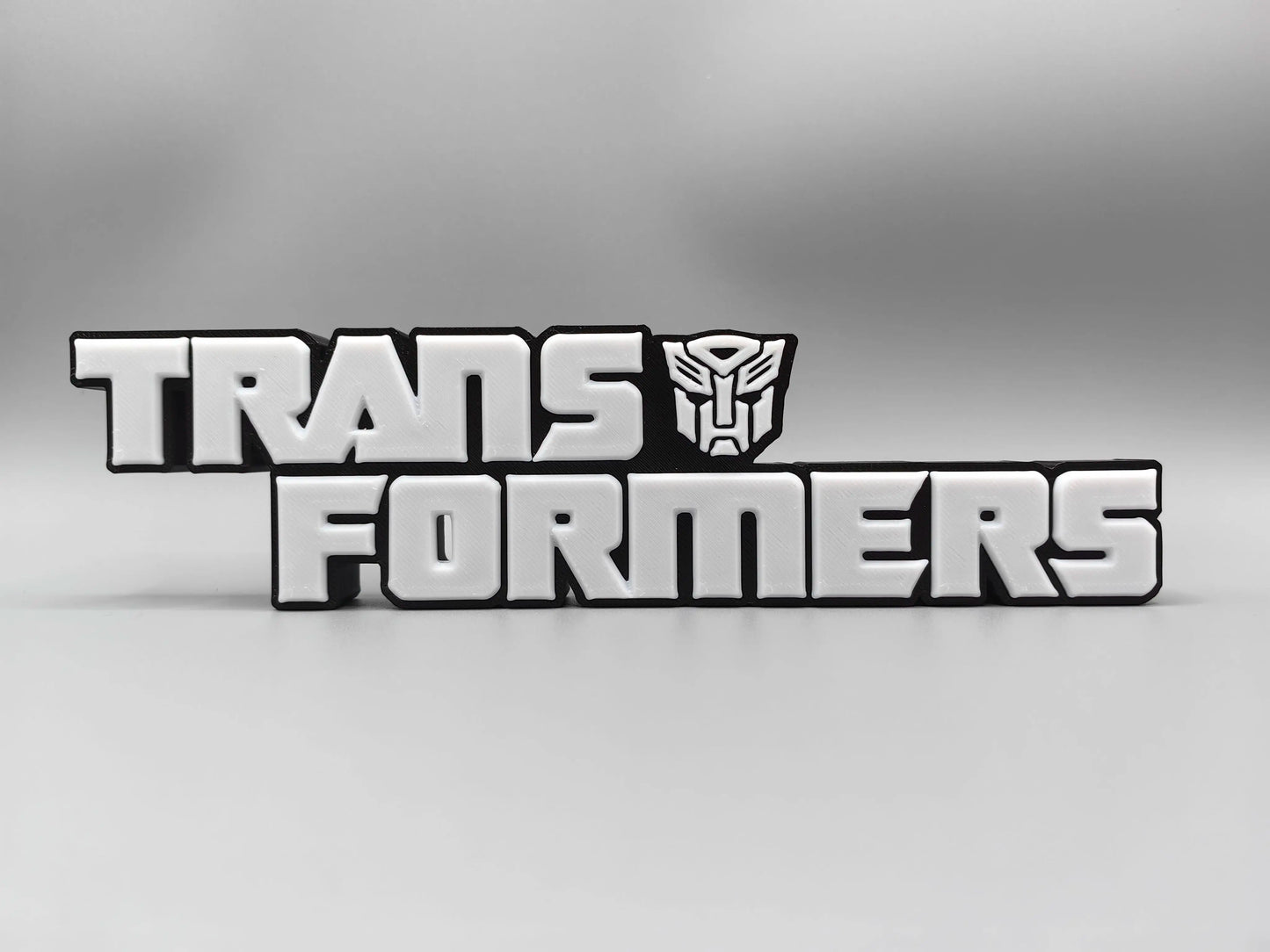 Plaque Transformers Logo Argenté Monochrome — Décoration Bureau Édition Métallisée