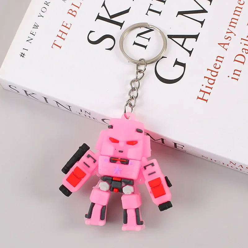 Porte-clés figurine robot rose, yeux rouges, style cartoon, sur un livre blanc – Transformers.