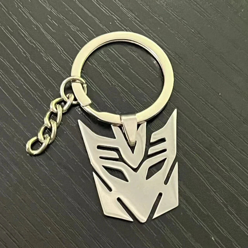 Porte-clés métal logo Decepticon argenté sur fond noir, design stylisé – Transformers.