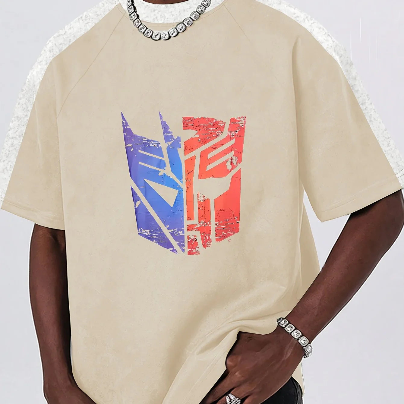 T-shirt beige avec logo Transformers bicolore bleu et rouge usé, porté par un homme stylé – Transformers.