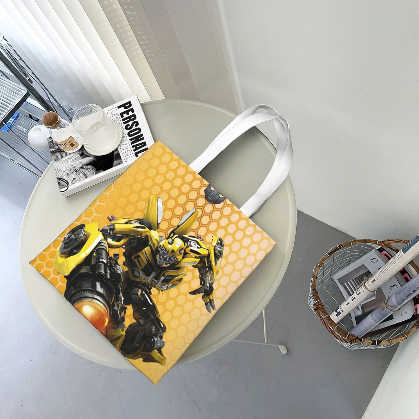 Sac cabas jaune motif nid d’abeille avec Bumblebee en action, posé sur une table ronde – Transformers.