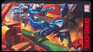 Boîte de figurines Transformers illustrant deux robots en action sur fond industriel coloré – Transformers.