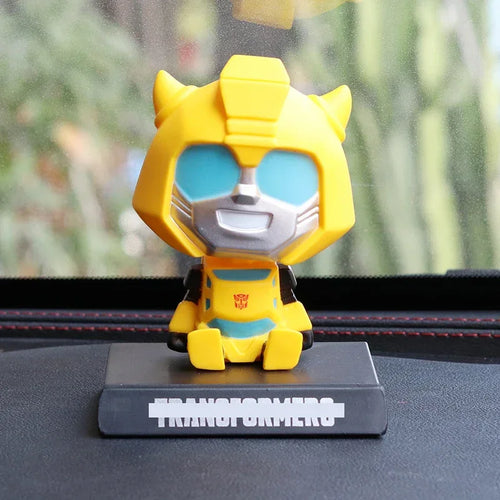 Figurine Bumblebee jaune assise à grande tête sur socle noir, fond flou – Transformers.